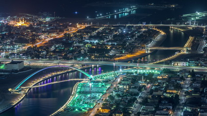 Fototapeta na wymiar Dubai water canal with footbridge aerial night timelapse from Downtown skyscrapers rooftop