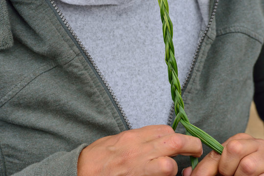 Braiding Sweetgrass demonstration: holding one end with teeth while braiding
