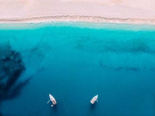 Aerial top down view two yachts stand at sea near white sandy beach