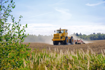 Obraz premium A farm tractor cultivates land after harvesting grain.