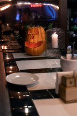A pumpkin in the form of a smiling face is standing on the bar on the eve of the helloween holiday