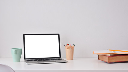 Creative workspace with laptop computer, books, colour pencil and coffee mug.