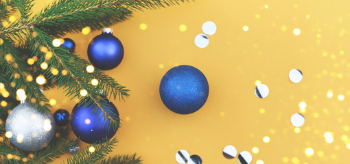 Fototapeta na wymiar Christmas tree branch decorated with blue toys on an orange background.