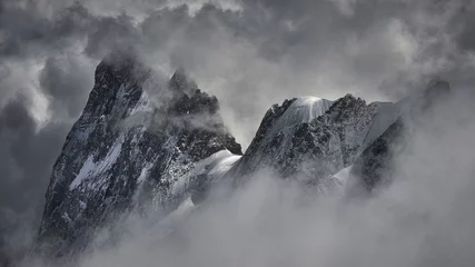 Gardinen Magical shot of a beautiful snowy mountain peak covered with clouds. © Denis/Wirestock