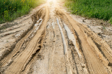 Soil road that has traces of slippery tires due to wet rain. A guiding light that goes forward with...