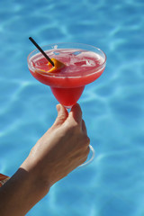 A glass of vodka cranberry drink next to the swimming pool, summer party vacation concept