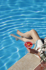 A glass of vodka cranberry drink next to the swimming pool, summer party vacation concept