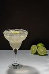 Lemon margarita in glass cup on black background