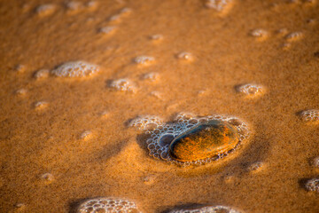 sandy beach with pebble and spray of the surf