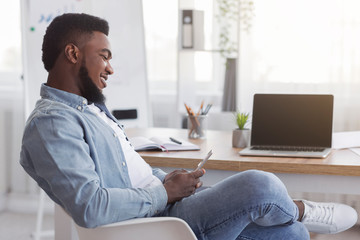 Carefree employee using smartphone at work browsing internet or messaging
