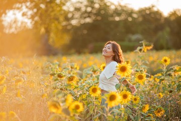 Young Asian woman with curly hair in a field of sunflowers at sunset. Portrait of a young beautiful asian woman in the sun.