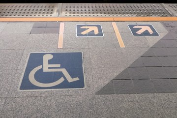 Handicapped sign on tile platform, Waiting line for disabled people entrance to the train, Behind yellow line for safety.