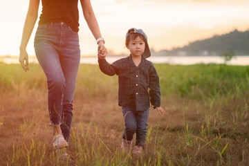Little asian girl walking in the nature with her mom, Mother holding hands of her daughter. Children walk to explore nature for the first time.