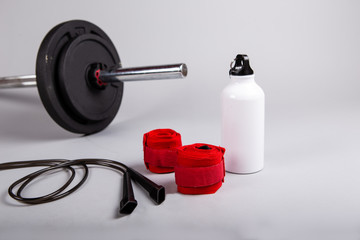 Training equipment: weights, water bottle, rope and hand bands. Sport accessories, grey background