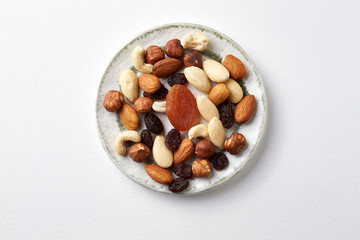 Nuts, raisins and apricots on white paper background. Concept for healthy snack. Top view. Copy space. 