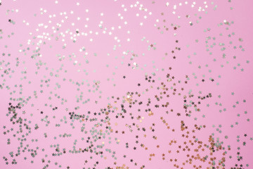 Confetti of gold stars glisten on a pink background. Festive holiday pastel backdrop.