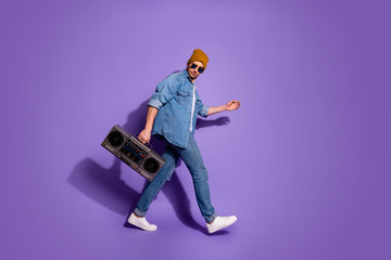 Naklejka premium Full length body size profile side photo of carefree moving attractive handsome guy holding sound recorder with hands going to discotheque isolated over purple bright color background