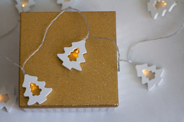 Obraz premium golden box with christmas present and wooden garlands on a white background