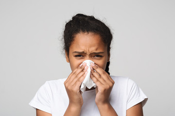 Teen girl blowing nose over grey background