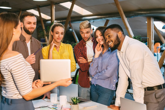 Young woman showing digital tablet to colleagues in office - Powered by Adobe