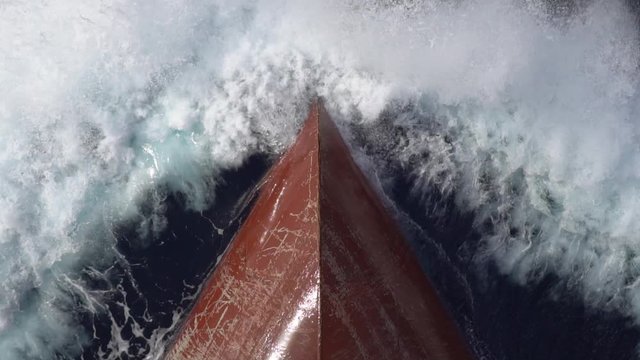 red metal bow of a cargo ship cuts a sea waves with white foamy splashes