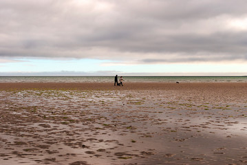 Fototapeta na wymiar One man and a woman walking on sandy beach. One father and his daughter enjoying the day. family.