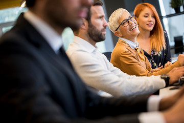 Businessman executive in group meeting with other businessmen and businesswomen in modern office with  computer