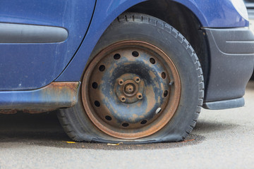 Flat tire on the rusty disc of an old car.