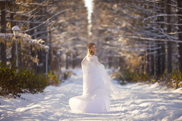  beautiful girl in a white dress walks in the winter forest