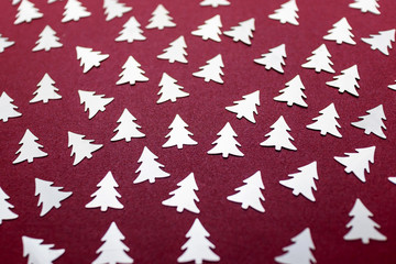 Festive silver Christmas tree-shaped confetti. Mother of pearl red background. New Year and...