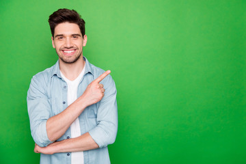 Photo of positive cheerful attractive handsome man pointing at empty space with forefinger smiling...