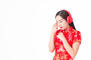 Obraz na płótnie Canvas The image of an Asian girl in a traditional Chinese dress, Cheongsam, black hair, so sad, wearing headphones to listen to music.