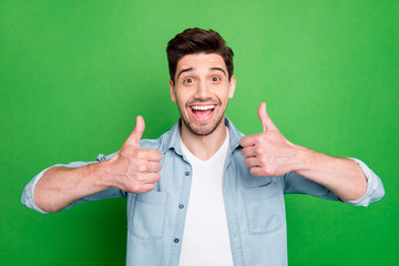 Photo of amazing business guy raising thumbs up approving good job quality results wear casual denim shirt isolated over green color background