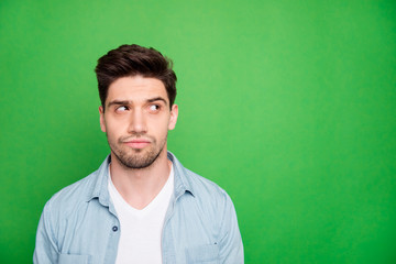 Obraz premium Photo of attractive bristled bearded man looking into empty space trying to find necessary information there isolated over green vivid color background