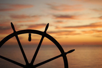 Ship rudder with sunset sea on background.