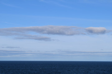 Dark blue sea with smooth water surface behind of moving cruise ship and endless skyline
