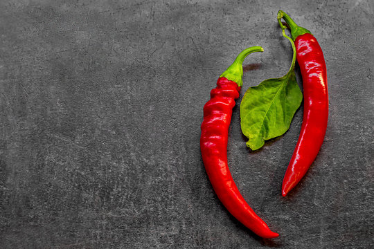 two red chili peppers on a dark background space for text