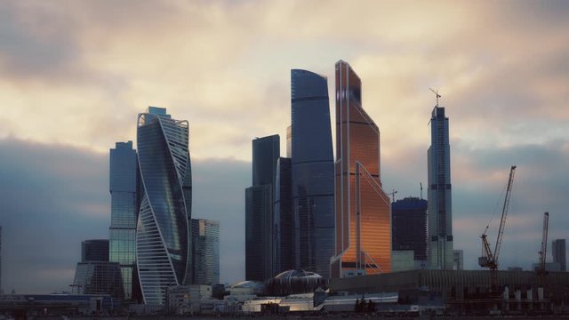 Cityscape of the financial district. Moscow City. Futuristic skyscrapers. Panoramic view. Cars are moving along the promenade. Sunset, twilight. Purple and orange clouds in the sky. Ultra HD footage