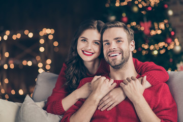 Closeup photo of adorable couple spending holly christmas eve in decorated garland lights room near...