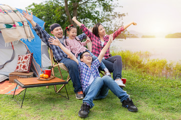 people group and sunlight, asian family travel and camping in forest, they sitting and feeling cheerful and happy at lakeside, they show cheer emotion, family activity, adventure and travel