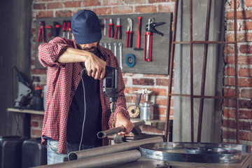 Metalworker drilling a hole in a metal pipe