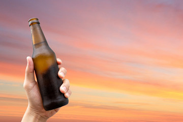 Hands holding a beer bottle and happy enjoying harvest time together to clinking glasses at outdoor...