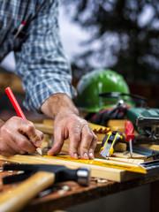 Adult carpenter craftsman with a pencil and the carpenter's square trace the cutting line on a wooden table. Construction industry, housework do it yourself. Stock photography.