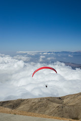 Paraglider silhouett against a cloudy blue sky.
