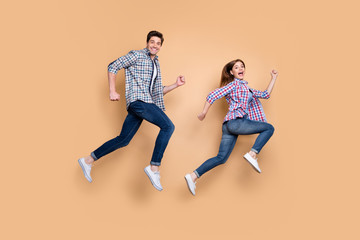 Fototapeta na wymiar Full length body size side profile photo of gorgeous beautiful nice charming couple with him running after her and her trying to escape him in jeans denim checkered shirt isolated beige pastel color