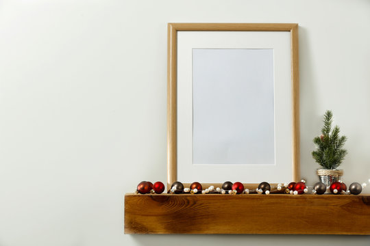 Christmas decorations in bright shiny colors with Christmas lights, picture frames and blurred white wall background.