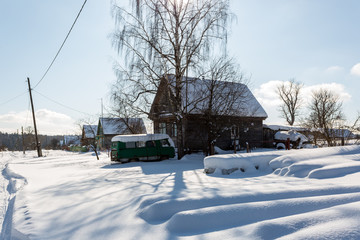 Fototapeta na wymiar Early winter morning. Street in traditional Russian village in snowy frost winter