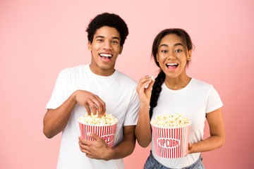 African-american couple eating popcorn and watching comedy film