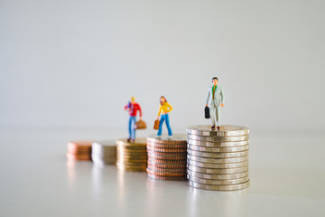 Miniature people, group of business team standing on stack coins using as business and financial...