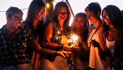 Friends celebrating together with love and friendship concept - group of females people smile and have fun by night with sparklers and laughs -   new year eve party celebration